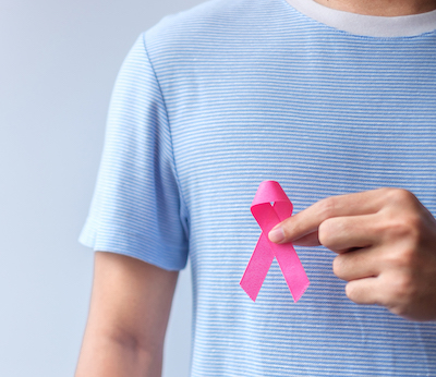 Hombre sosteniendo una cinta rosa de concientización sobre el cáncer de mama