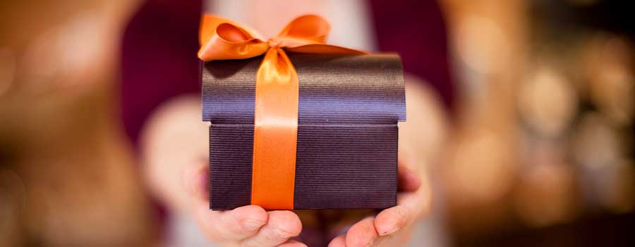 Hands holding gift box wrapped in gold ribbon